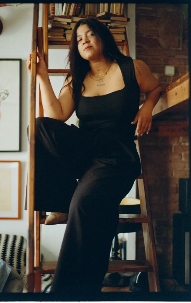 Retrato de Nadieska sentada junto a una escalera de madera.